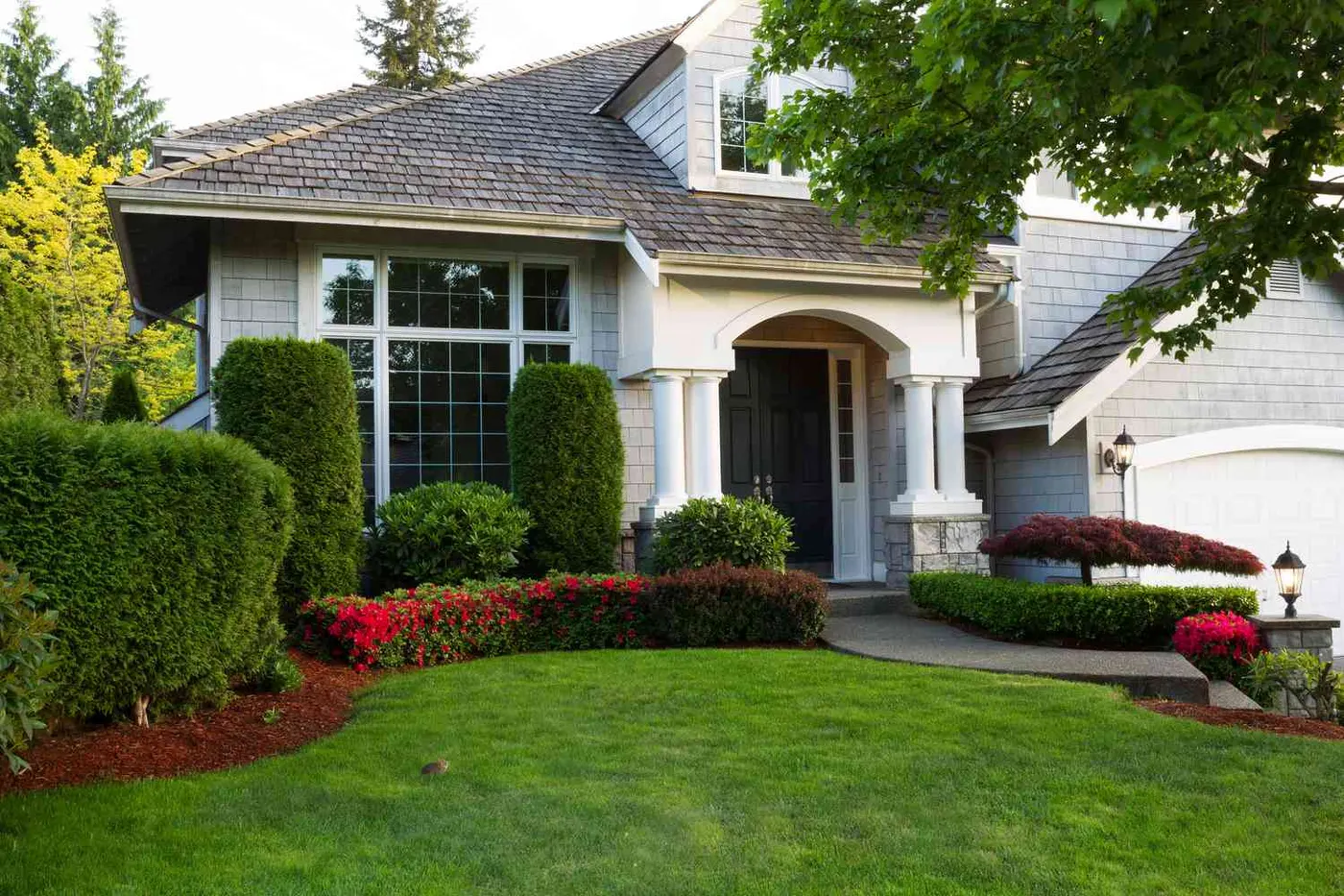 A house with trimmed shrubs and a green lawn