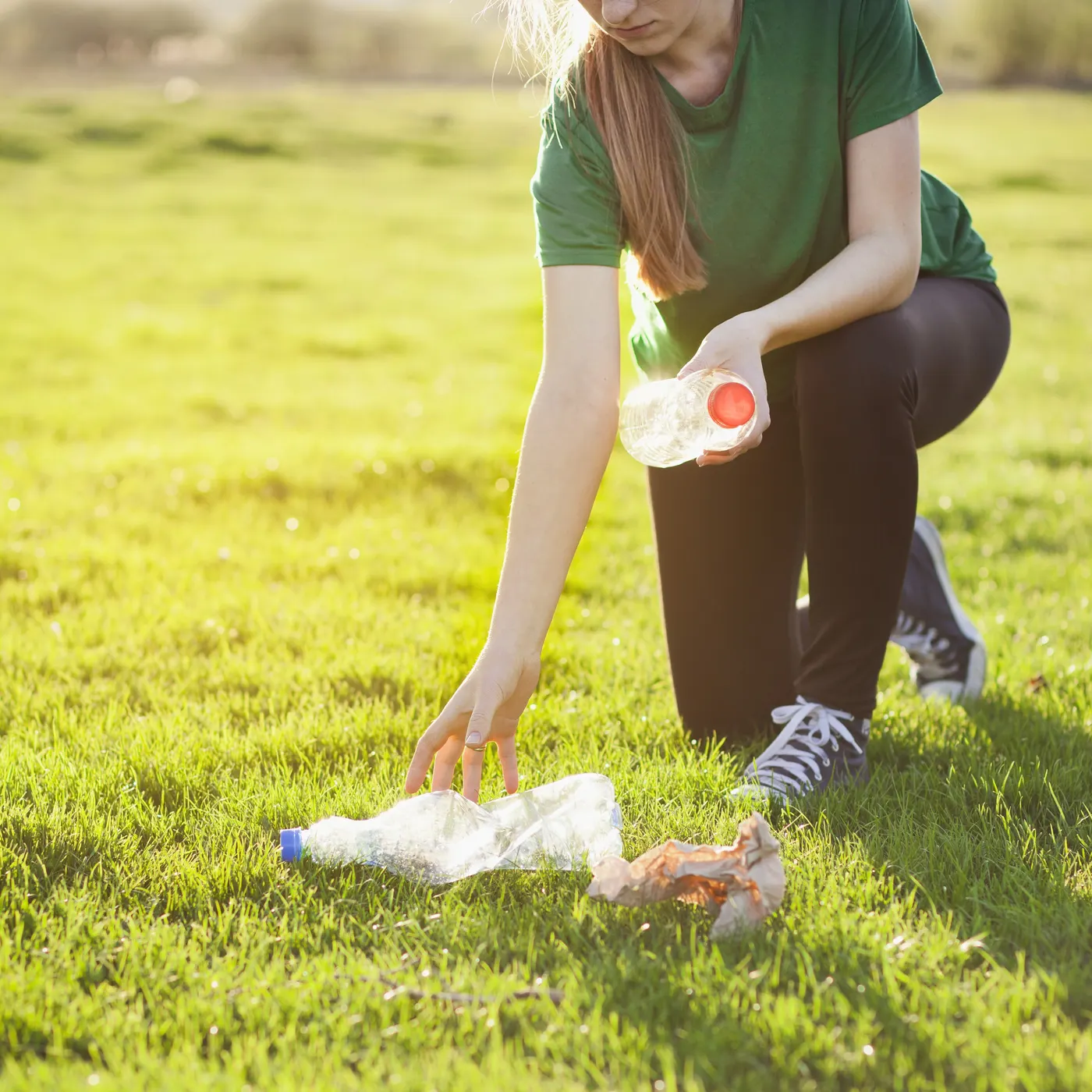 A woman kneeling to tend a green lawn